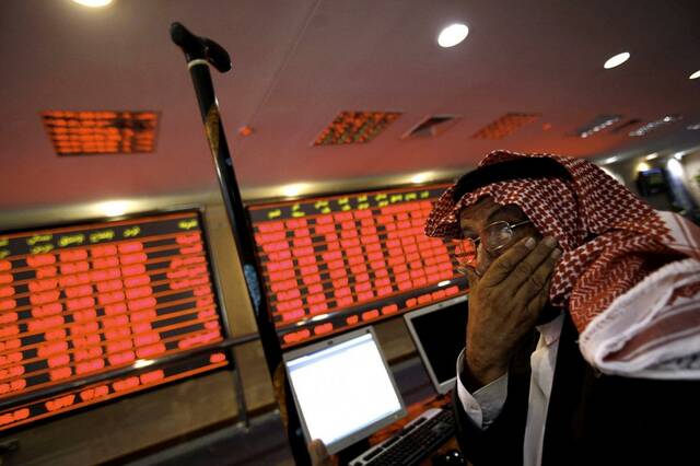 متداول يتابع أسعار الأسهم بقاعة سوق قطر المالي - أرشيفية
